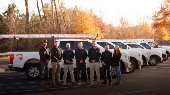 Team members standing in front of work trucks