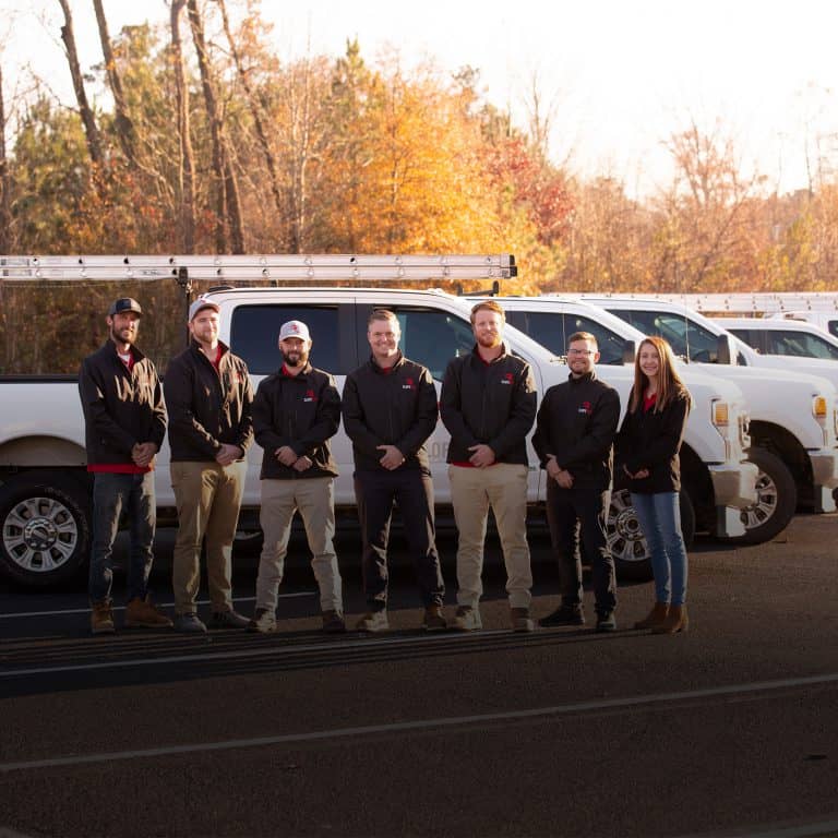 Team members standing in front of work trucks