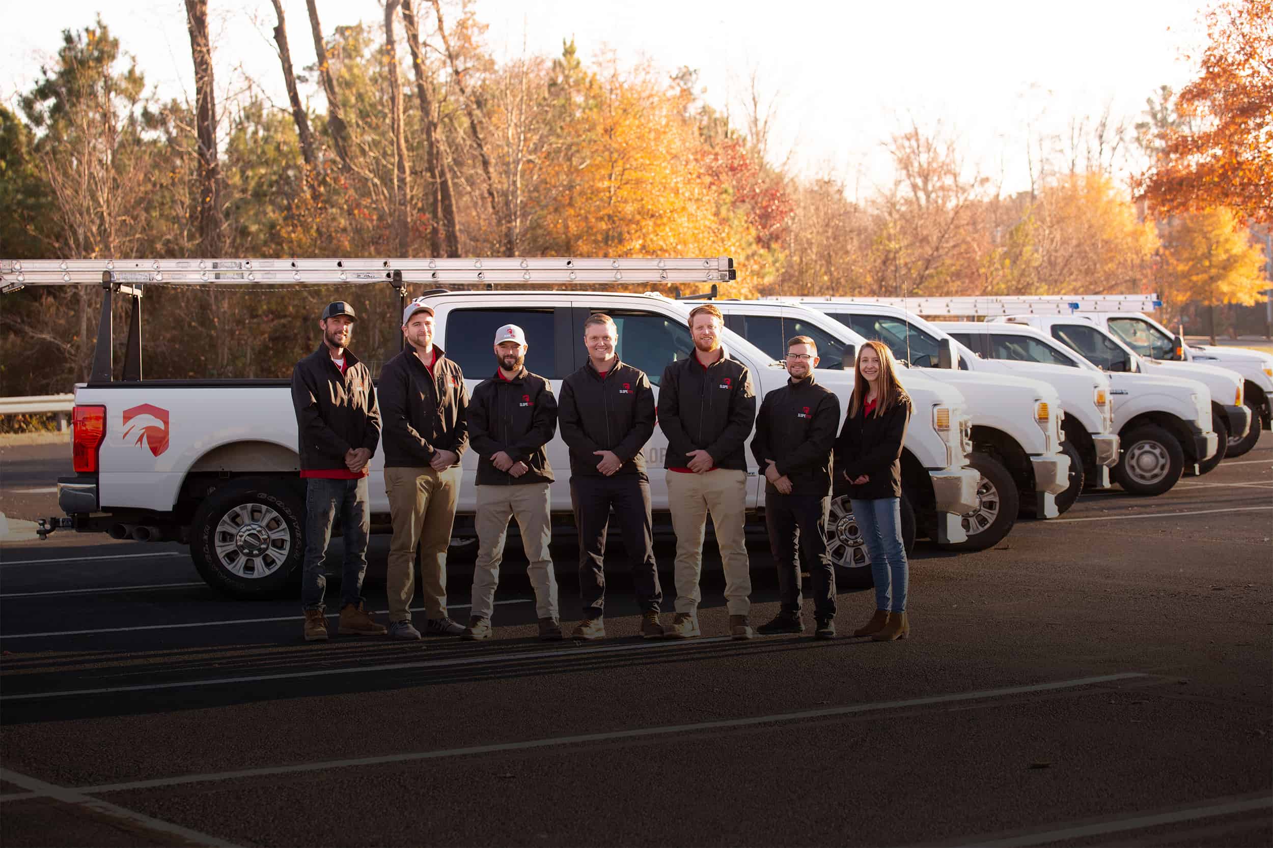 Team members standing in front of work trucks